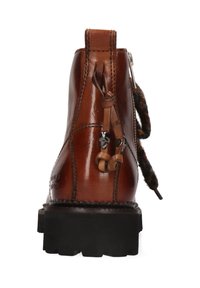 Stivale alla caviglia in pelle marrone con suola nera spessa, zip laterale e frange decorative. Presenta cuciture visibili e un tacco accentuato.