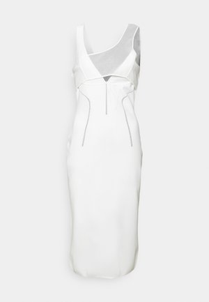 Robe blanche avec une silhouette cintrée, présentant un mélange de tissus lisses et texturés, des découpes angulaires et des détails en argent.