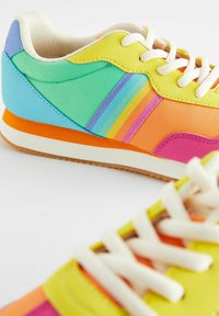 Tenis colorat featuring textile galben, verde, albastru, roz și portocalie. Material texturat, sireturi albe și talpă din cauciuc.