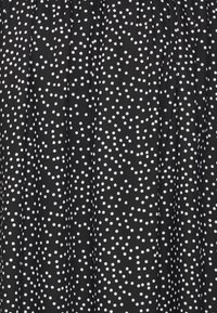 Tessuto nero con pois bianchi, caratterizzato da una texture arricciata, creando una superficie decorata con dimensioni di pois variabili.