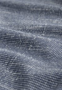 Getextureerde blauwe stof met een geweven patroon en witte spikkels. Het oppervlak heeft een zachte, licht glanzende afwerking.