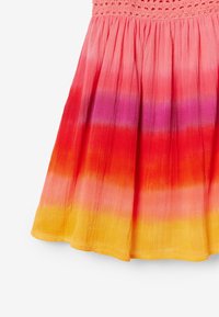 Falda de tie-dye con una cinturilla fruncida y texturizada. Los colores van de un vibrante rojo a naranja, amarillo y un sutil púrpura. Tejido ligero.