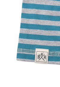 Randigt tyg med växlande teal- och ljusgrå ränder, med en texturerad yta och en vävd etikett med korsade symboler och bokstäverna "B R."