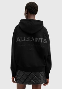 Black hoodie featuring textured "ALLSAINTS" logo on the back, with additional text in Japanese and "LONDON" below. Soft fabric, relaxed fit.