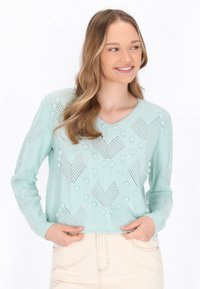 Minzgrüner Pullover mit V-Ausschnitt, strukturiertem Strickmuster mit erhabenen Punkten und Zickzackmustern, langen Ärmeln und einer cropped Passform.