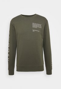 Olivově zelená mikina s dlouhým rukávem vyrobená z bavlněné směsi. Na hrudi a rukávu je bílý text, má žebrované manžety a lem.
