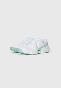 Un par de zapatillas deportivas blancas con acentos en azul aguamarina, suelas texturizadas y el logo de Nike en forma de swoosh, anguladas ligeramente hacia la derecha sobre un fondo liso.