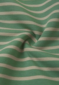 Zielony materiał w białe poziome paski, posiadający miękką, prążkowaną strukturę. Materiał jest lekko pognieciony, co podkreśla wzór pasków.