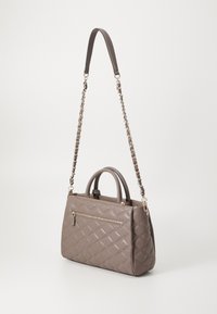 Bolso beige acolchado con asas superiores y una correa de cadena para el hombro. Presenta un bolsillo con cremallera en la parte frontal y una textura de cuero suave.