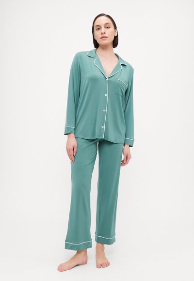 Teal pajama set in soft fabric, featuring a button-up shirt with a pocket and contrasting white piping, paired with loose-fitting pants.