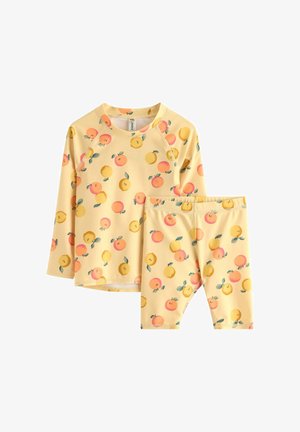 Żółty komplet z długim rękawem i szortami z wzorem pomarańczowych i żółtych owoców oraz zielonych liści na białym tle.