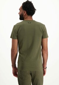 Olivevihreä lyhythihainen t-paita, joka on valmistettu puuvillasta, ja jossa on pyöreä kaula-aukko sekä pieni logo-tyyli niskassa. Silkkinen pinta, istuva malli.