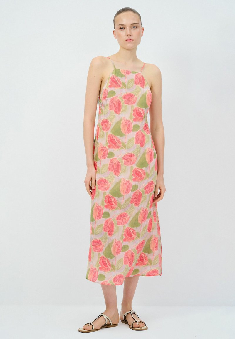 Maxi-jurk van lichte stof met een bloemenpatroon in roze en groen. Spaghetti-bandjes en een relaxed fit, gecombineerd met platte sandalen.