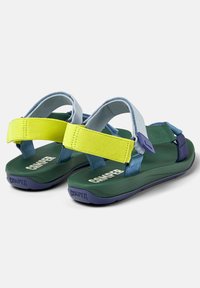 Bageste udsigt af grønne sandaler med blå og gule stropper. Letvægtsdesign med justerbare stropper og en tekstureret sål med logo.
