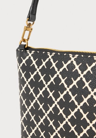 Coin de sac à main à motif noir et blanc avec fermeture éclair dorée et fermoir doré attaché à une sangle noire.