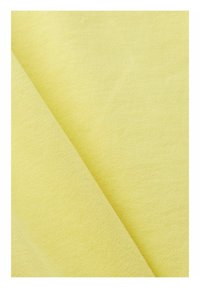 Světlá žlutá látka má jemnou texturu a hladký povrch. Materiál vykazuje jemný lesk a je složený tak, aby ukázal vrstevnatý vzhled.