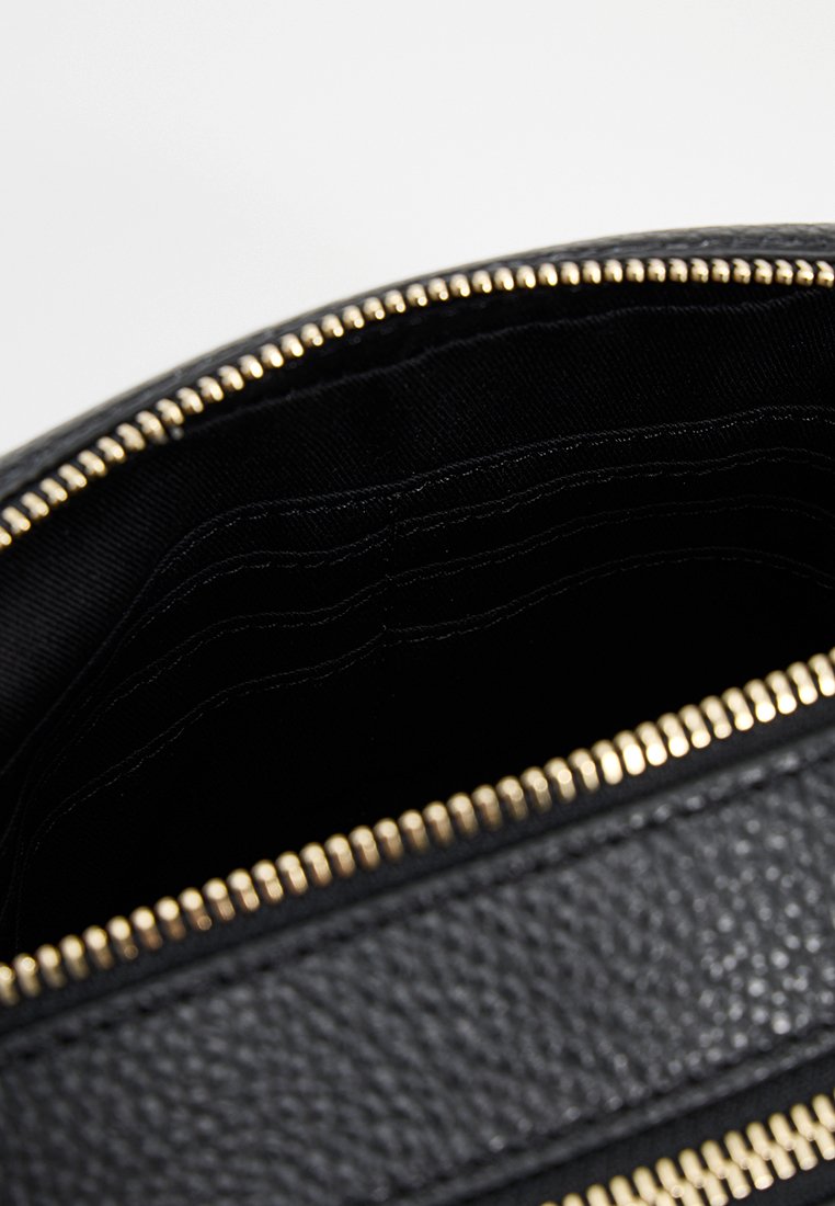 Intérieur de sac à main noir texturé avec fermeture éclair dorée, comportant plusieurs emplacements pour cartes et doublure noire lisse.