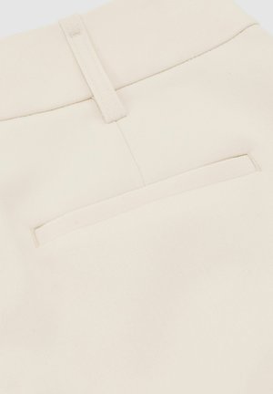 Krupni plan bež hlača od tkanine koje prikazuju stražnji džep i petlju za remen s vidljivim detaljima šavova.