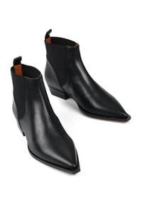Czarne skórzane botki za kostkę z szpiczastymi noskami, elastycznymi panelami po bokach i niskim obcasem typu blok. Wnętrze ma kontrastującą brązową wyściółkę.
