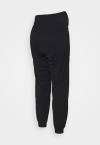 Calças de jogging pretas feitas de tecido macio, com um corte relaxado, faixa elástica na cintura e punhos ajustados com detalhe de franzido nas laterais.