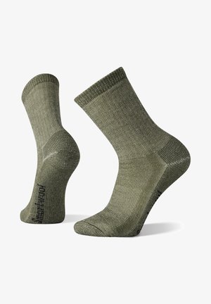 Calzini a coste di colore verde oliva con tallone e punta rinforzati. Il materiale sembra essere texturizzato e presenta un polsino elastico liscio per una vestibilità sicura.