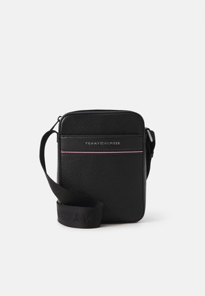 Borsa a tracolla nera con texture, tracolla regolabile, logo Tommy Hilfiger sul davanti e sottili strisce rosse e bianche sotto il logo.