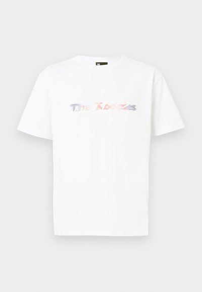 Άσπρο T-shirt με κοντά μανίκια, με πολύχρωμο, ελαφρώς θολωμένο λογότυπο "The Kooples" στο στήθος, σε απλό φόντο.