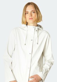 Chaqueta blanca impermeable con capucha, cierre de botones a presión, bolsillos laterales y detalles con cordón. Textura suave y corte relajado.