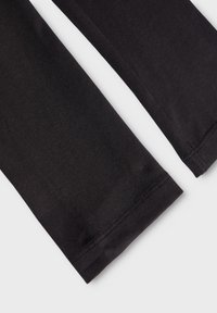 Zwarte katoenen legging met een gladde textuur, voorzien van eenvoudige stiksel-details aan de zoom en een nauwsluitend ontwerp voor comfort.