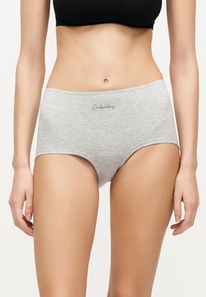 Kvinde iført lysegrå trusser med høj talje med teksten "Wednesday" foran, kombineret med en sort cropped top.