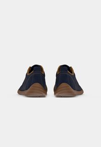 Chaussures en daim bleu marine avec des accents marron, design bas, bout arrondi et semelle en caoutchouc texturé. Détails de couture sur les côtés.