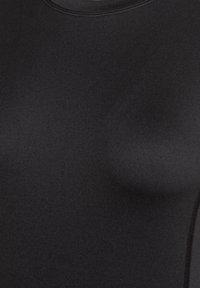 Svart åtsittande topp tillverkad av ett slätt, elastiskt material. Har en rund halsringning och sömlös konstruktion med en subtil lyster.