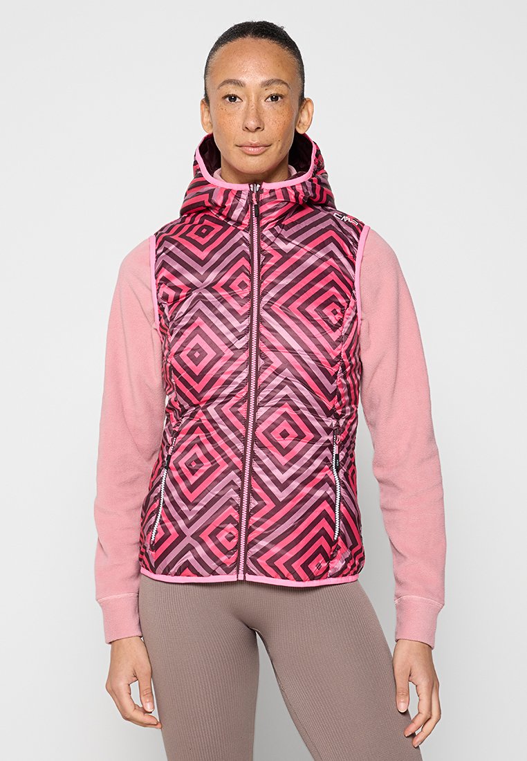 Bunte gepolsterte Weste mit einem geometrischen Muster in Pink und Lila, ausgestattet mit einem Reißverschluss vorne und einer Kapuze. Trägt man über einem pinken Langarmoberteil.