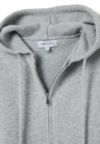 Felpa con cappuccio grigia con cerniera, realizzata in un tessuto morbido e strutturato. Presenta un cappuccio, una cerniera argentata e un'etichetta del marchio visibile all'interno del colletto.