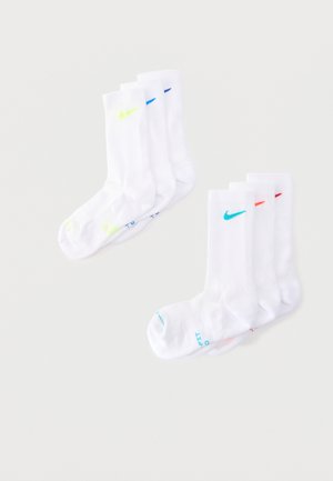Δύο σετ από τρία λευκά αθλητικά κάλτσες Nike, κάθε ζευγάρι με διαφορετικά χρωματιστά λογότυπα Nike swoosh και ταιριαστά σημάδια στα δάχτυλα.
