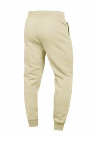 Beige Baumwoll-Jogginghosen mit schmal zulaufendem Design, elastischem Bund und Seitentaschen. Glatte Textur, gerippte Bündchen und minimalistische Nähte.