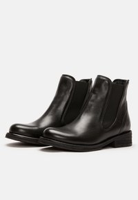 Bottines en cuir noir avec des panneaux élastiques sur les côtés, bout arrondi, petit talon empilé et finition lisse. Accent uées de détails de couture subtils.