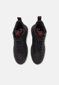 Zapatillas deportivas negras con parte superior de malla y sintética, acentos rojos, collar acolchado y logo en la lengüeta. Diseño con cordones y suela texturizada.