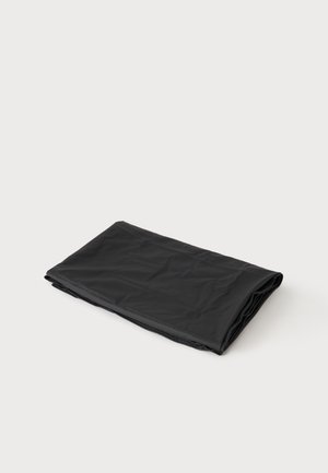 Folded black plastic sheet or tarp on a plain white surface, with slight wrinkles visible on its surface.