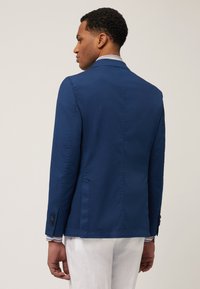 Marineblaues Sakko, strukturiertes Design, glattes Material, taillierte Passform, Schlitze hinten, kontrastierende gestreifte Manschetten, drei Knöpfe an den Ärmeln.