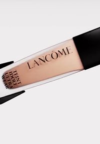 Lancôme foundationtube med en klar kropp, lys beige produkt, svart hette, og gullbokstaver. Har teksten "Teint Idole Ultra Wear".