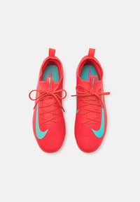 Chaussures de sport rouge vif avec une surface texturée, présentant des accents et des lacets teal. Forme de bout arrondi et sangle de traction au niveau du talon.