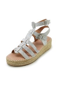 Glanzende zilveren sandalen met geweven banden en verstelbare gespen. Korken platformzool met een vlakke basis. Gladde leren binnenzool.