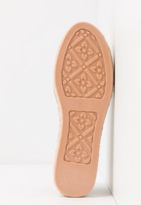 Semelle d'une chaussure, en caoutchouc beige avec un motif floral texturé. La taille "37" est visible. Les bords sont lisses, avec un design légèrement surélevé.