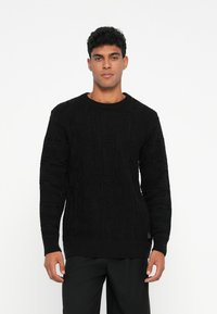 Schwarzer Strickpullover mit strukturiertem Muster, Rundhalsausschnitt und langen Ärmeln. Aus weichem Material mit gerippten Ärmeln und Saum.