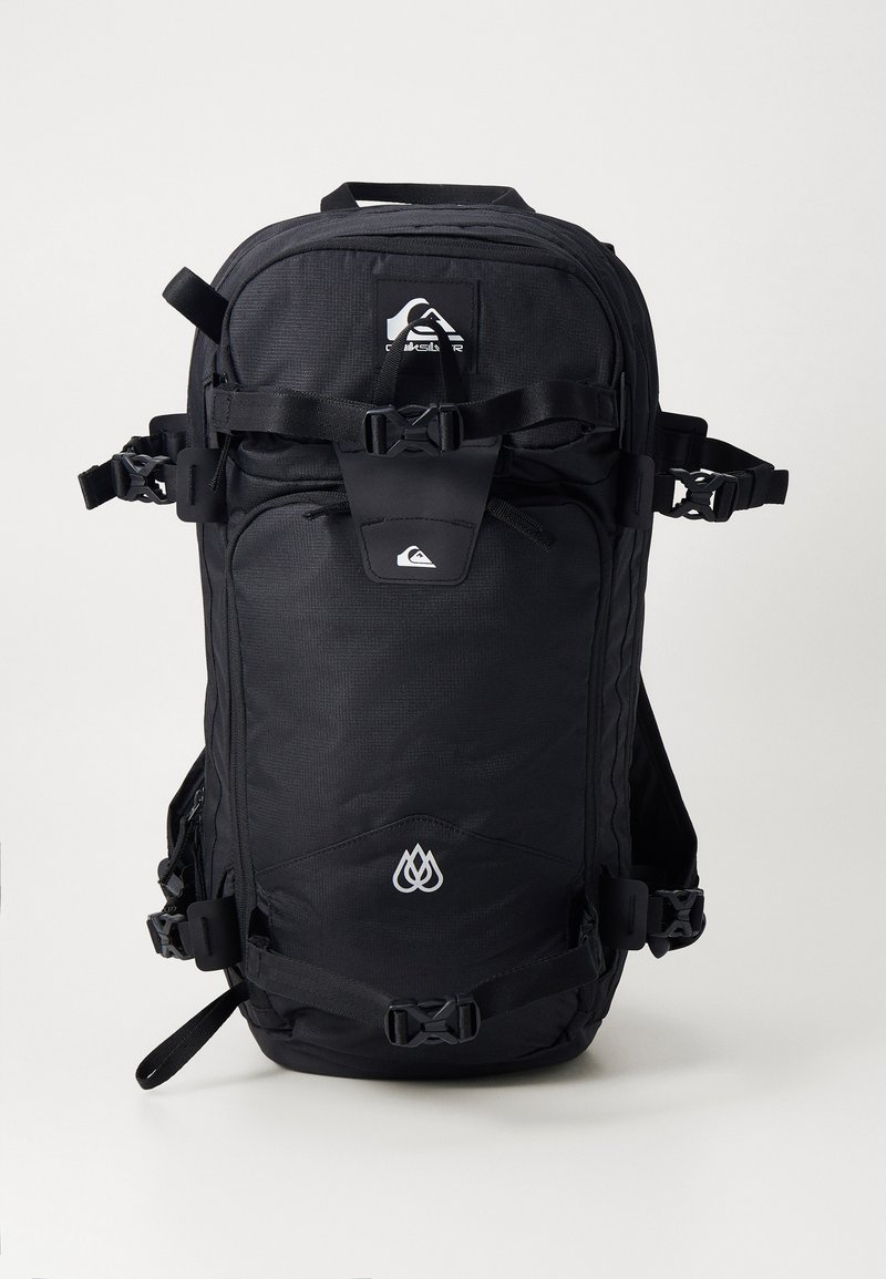 Black backpack with textured fabric, multiple adjustable straps, a front zip pocket, and white logo accents. Compact design for outdoor use.