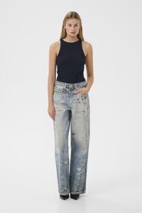 Ciemnoniebieski bezrękawnik w połączeniu z jasnoniebieskimi, szerokimi dżinsami z przetarciami. Dżinsy mają wyblakłe miejsca i liczne postrzępienia. Czarne buty na obcasie.