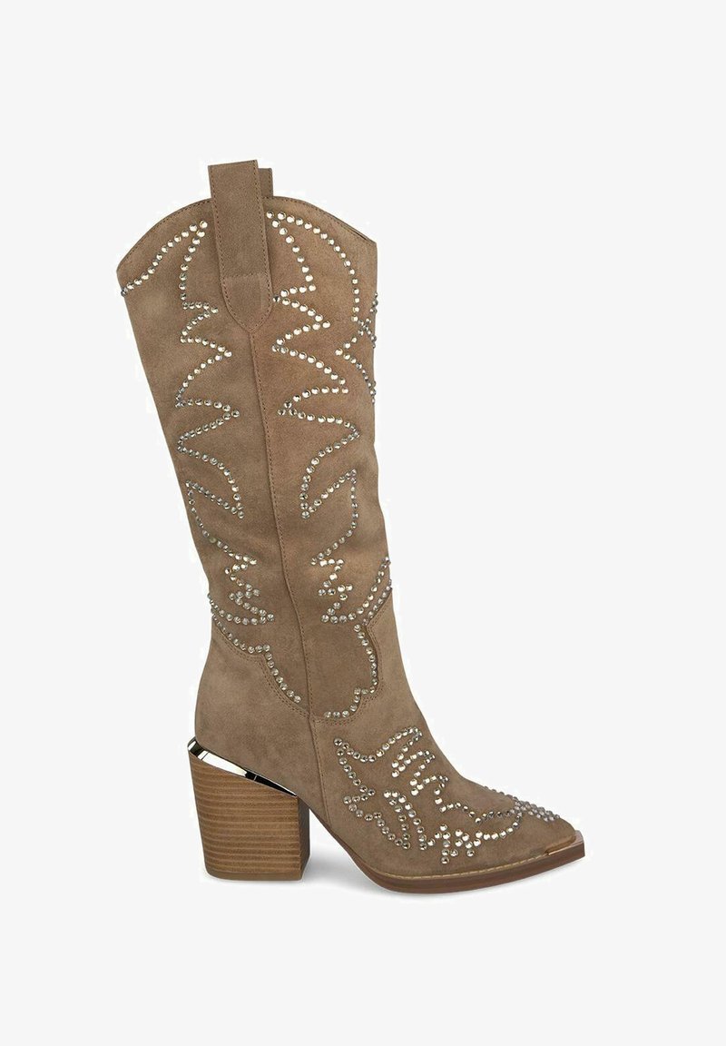 Bota vaquera de ante en color marrón, con adornos de tachuelas plateadas y costuras onduladas. Punta puntiaguda y tacón estructurado con textura de madera.