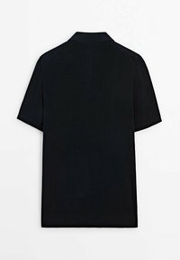 Zwart polo shirt met korte mouwen van gestructureerde stof en een klassieke kraag, weergegeven vanuit de achterkant op een witte achtergrond.