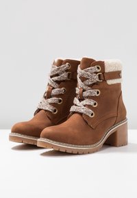 Bottines en daim marron avec une finition texturée, des lacets épais, des œillets dorés, une doublure en fausse fourrure et un talon carré. Semelle en caoutchouc pour une bonne adhérence.